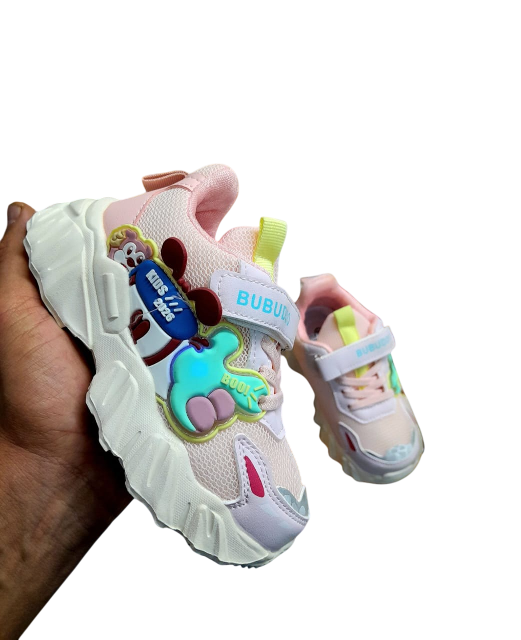 Zapatilla infantil de color gris y blanco con diseño de Mickey Mouse sostenida en la mano.