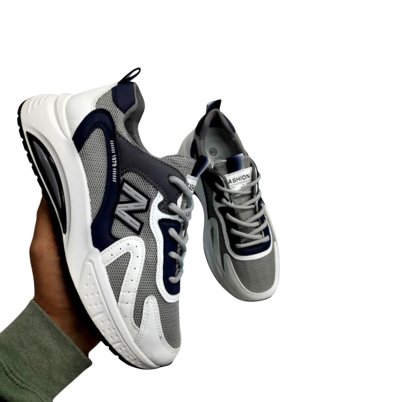 Una mano sosteniendo un par de zapatillas grises y azul marino con detalles en blanco.