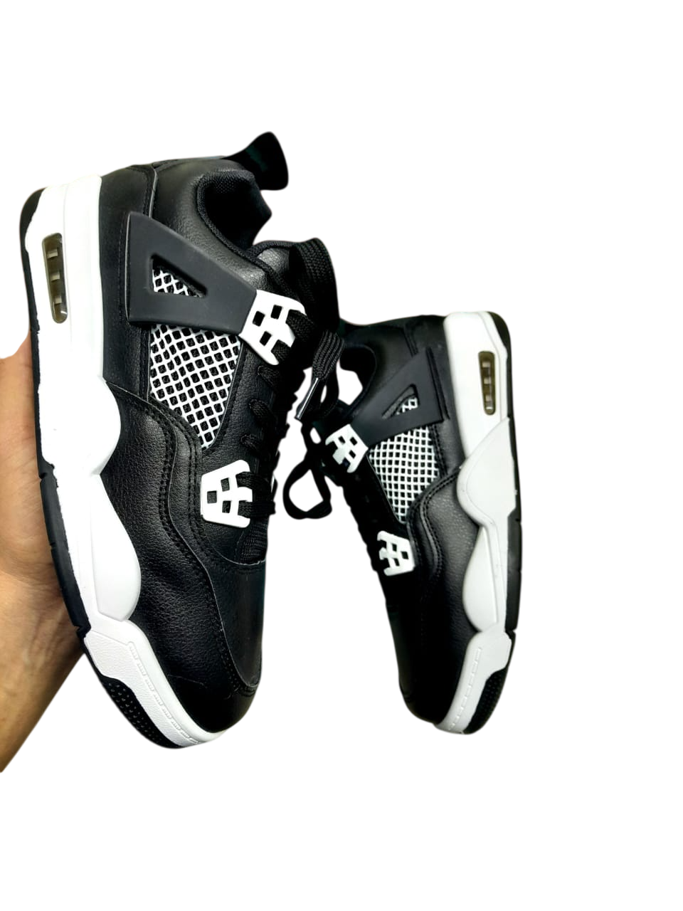 Mano sosteniendo zapatillas blancas y negras; diseño clásico.