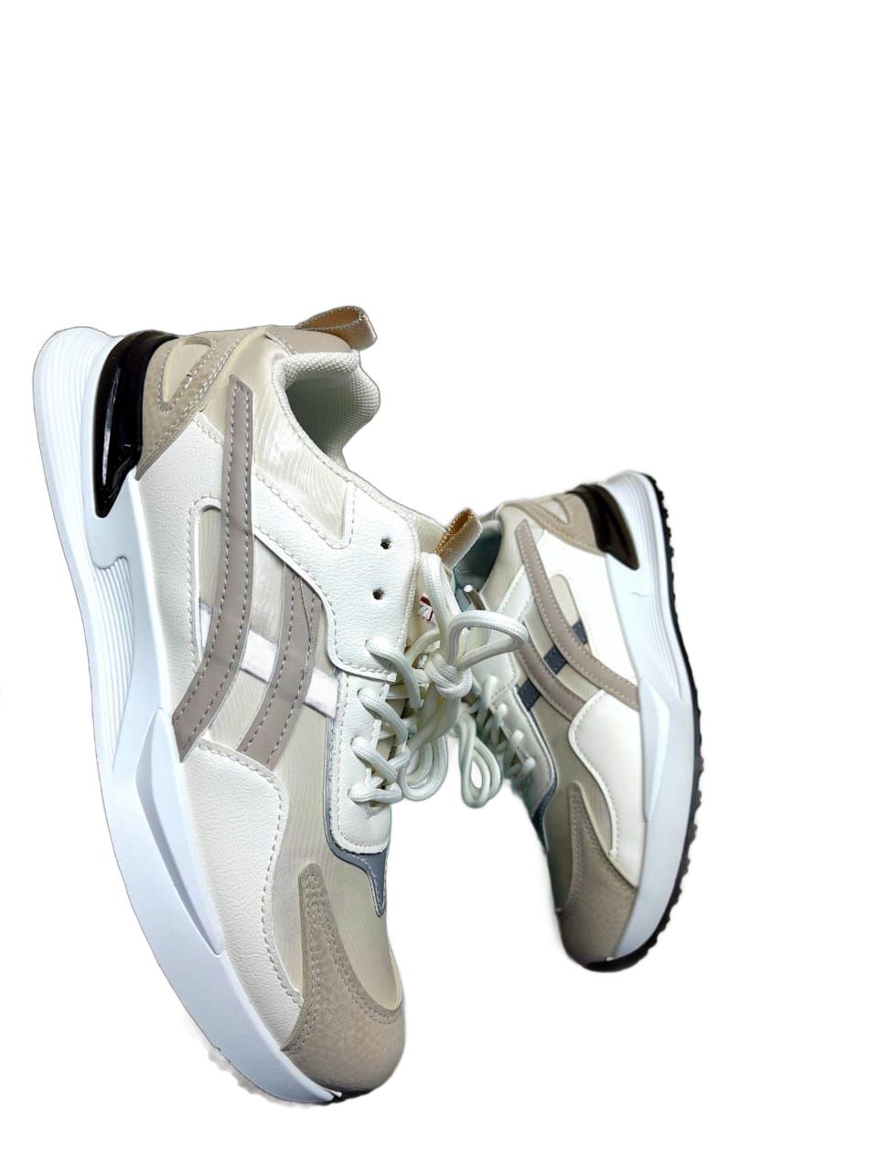 Zapatillas grises, blancas y verdes sostenidas por la mano de una persona sobre un fondo blanco.