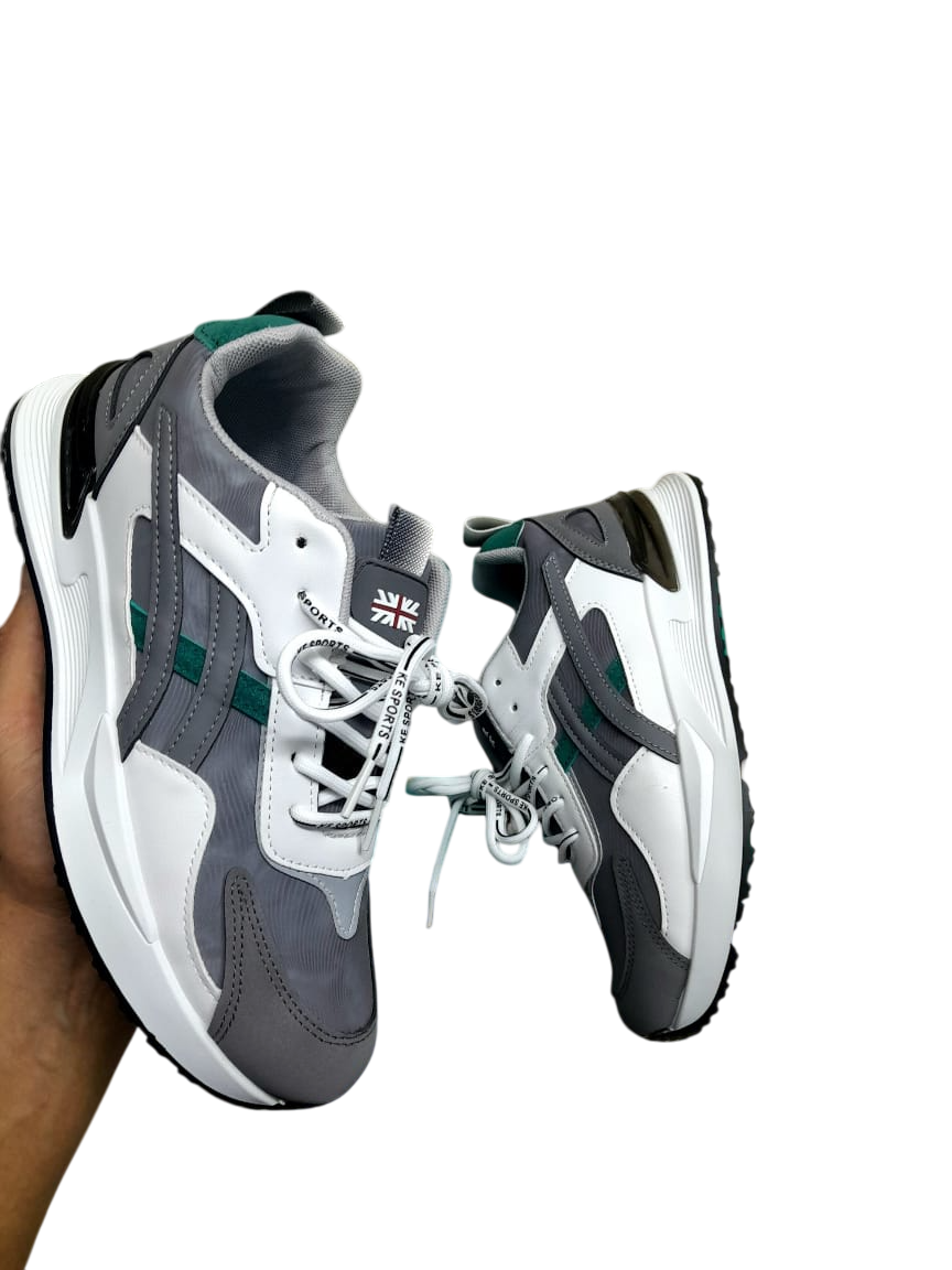 Zapatillas grises, blancas y verdes sostenidas por la mano de una persona sobre un fondo blanco.