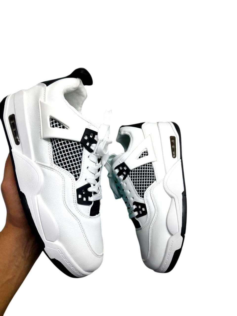 Mano sosteniendo zapatillas blancas y negras; diseño clásico.