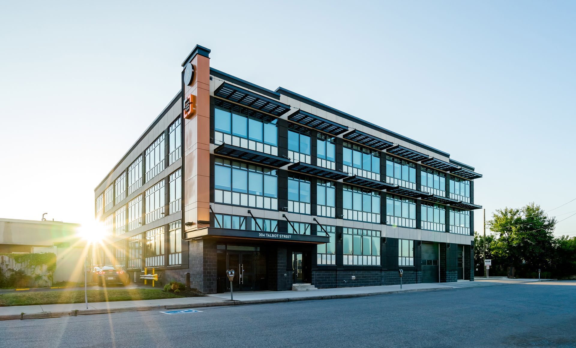 Modern office building with large windows, sun shining on the facade.