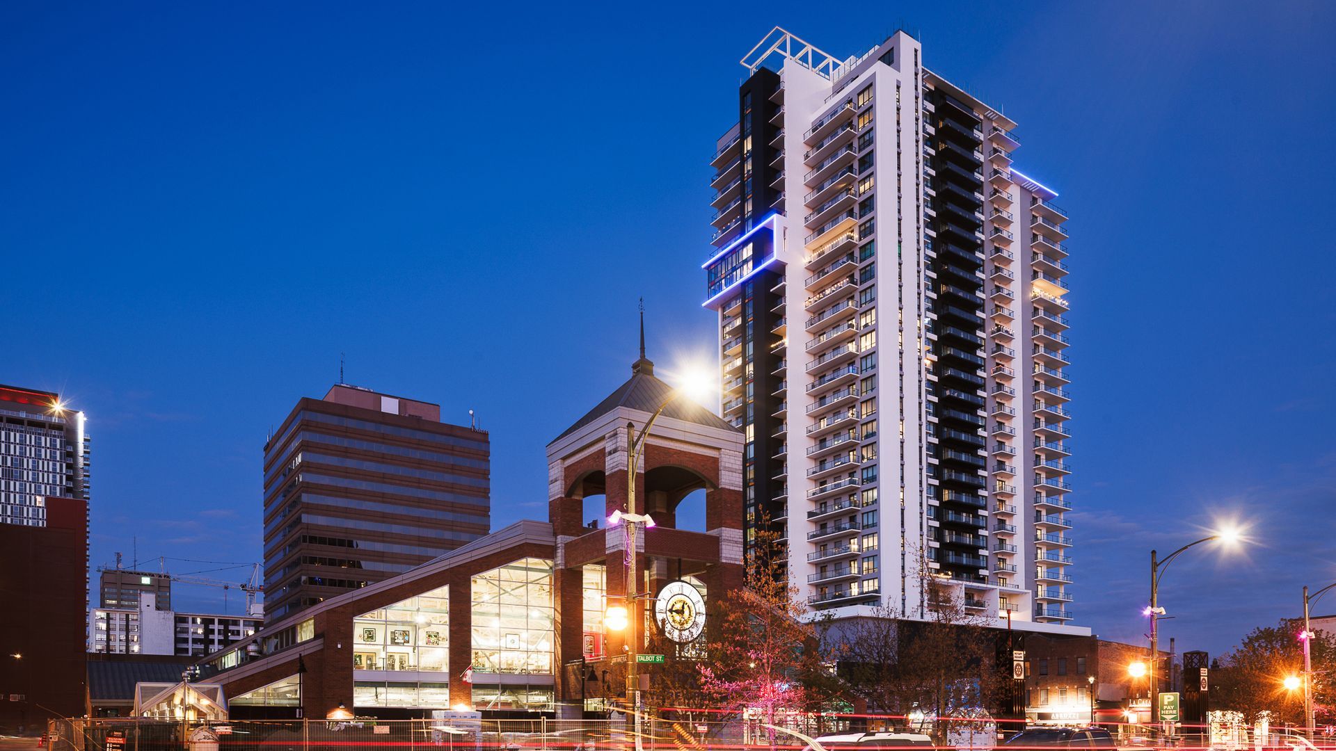 Clock tower and high-rise building in a city square with people gathered.