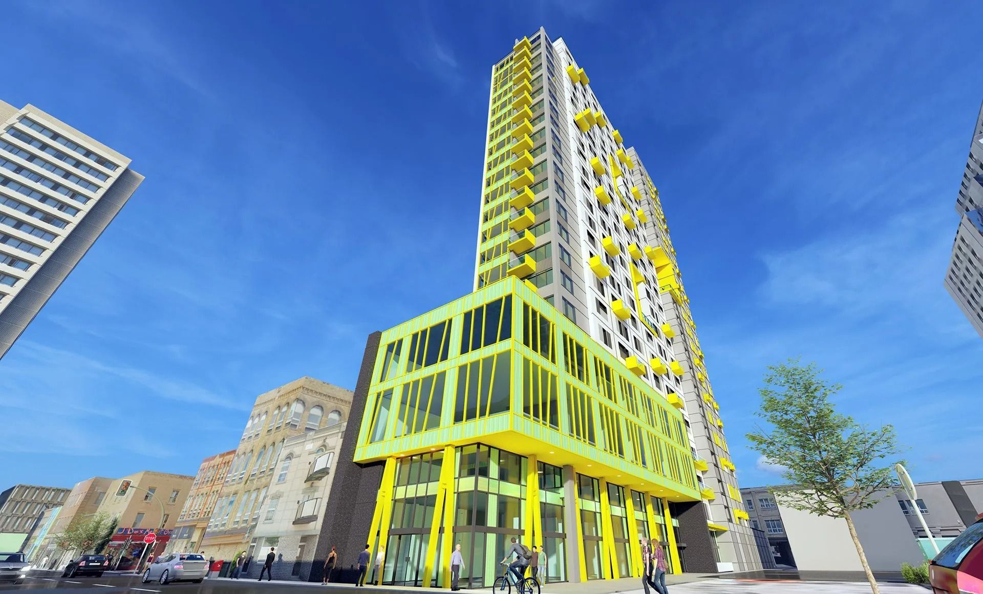Tall yellow and white building with green accents and storefronts on a city street under a blue sky.