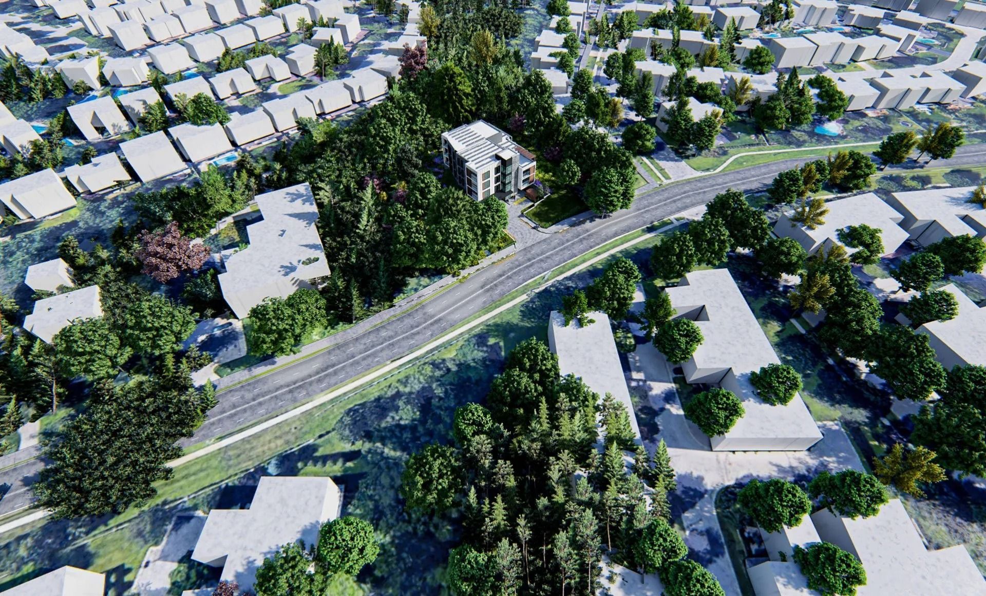 Aerial view of a road cutting through a dense tree-lined area with homes and buildings in the background.