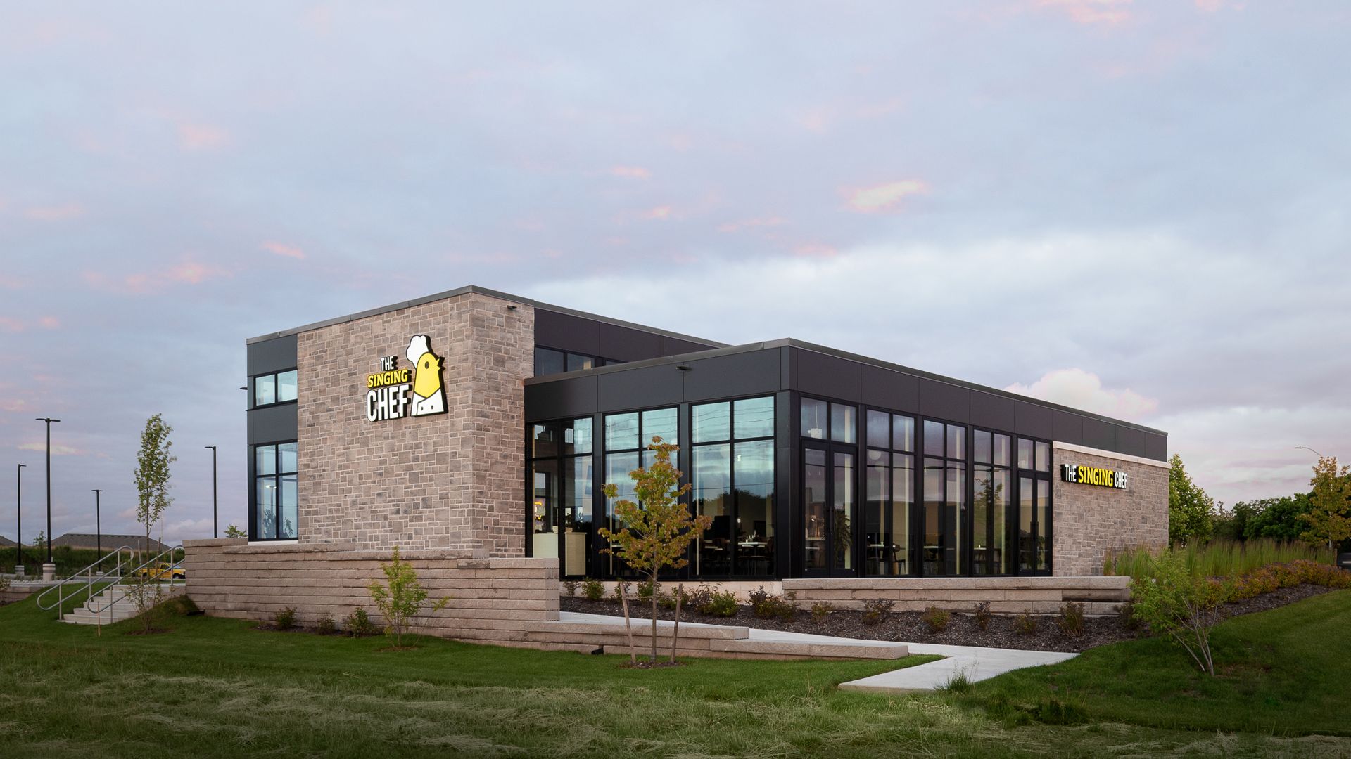 Modern building with stone and glass exterior, logo in yellow.