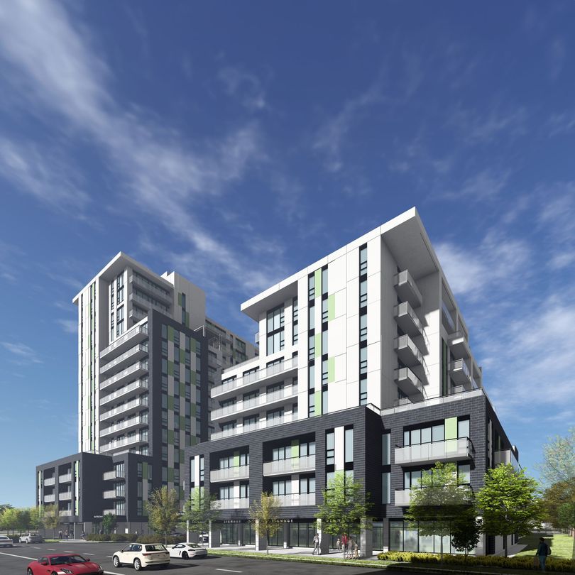 Multi-story modern apartment buildings with green and gray accents under a blue sky.