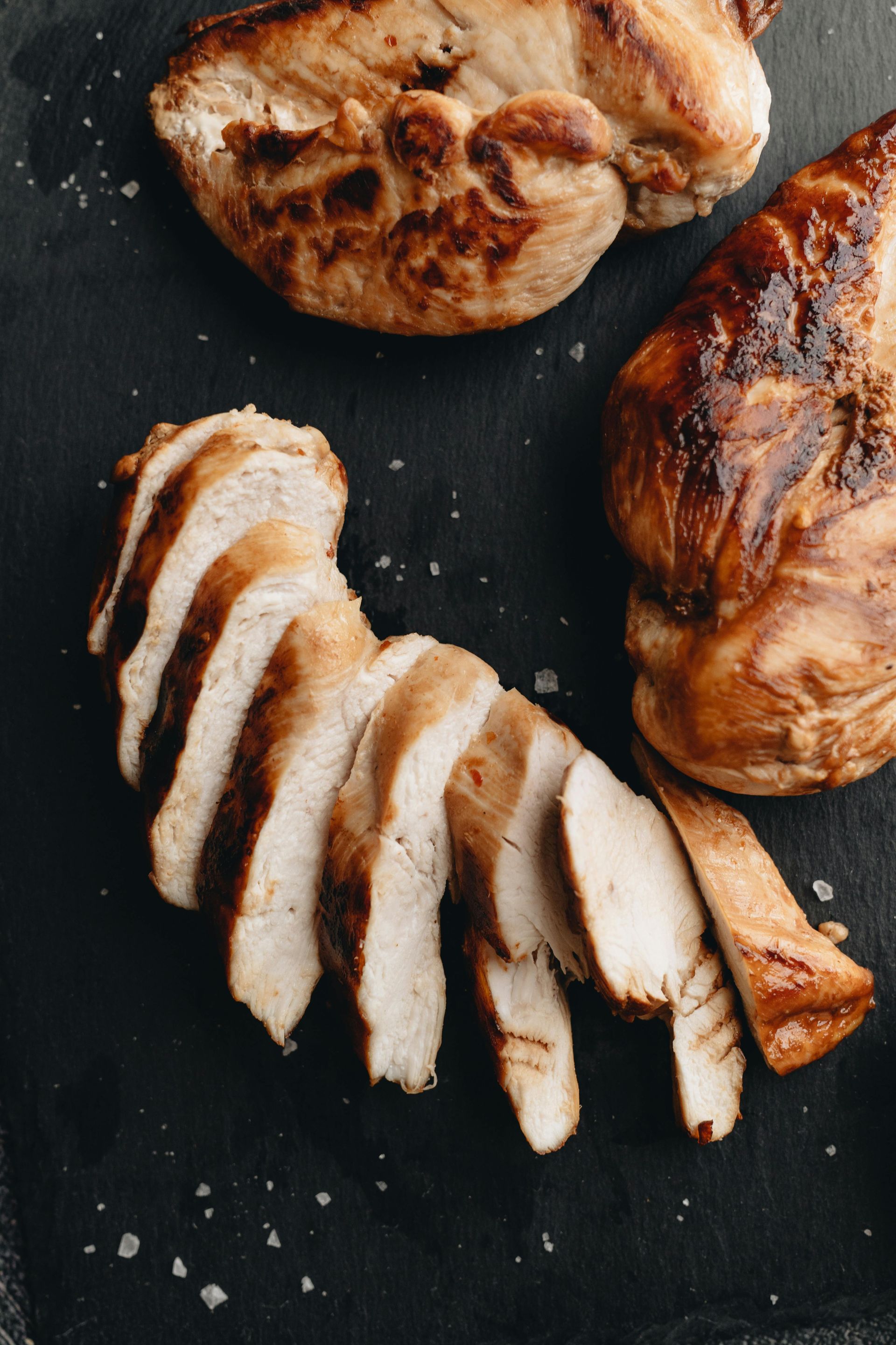 Drie sneetjes geroosterd brood, belegd met tonijn, rucola, rode ui en verse kruiden, in een grijze kom.