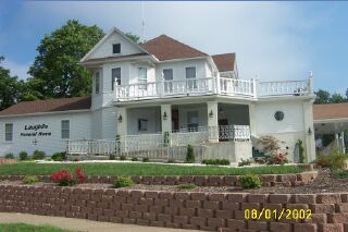 White funeral home with a brown roof and a sign for Richeson Funeral Home. Brick retaining wall and green grass in front.