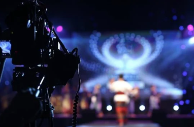 A camera is recording a group of people dancing on a stage.
