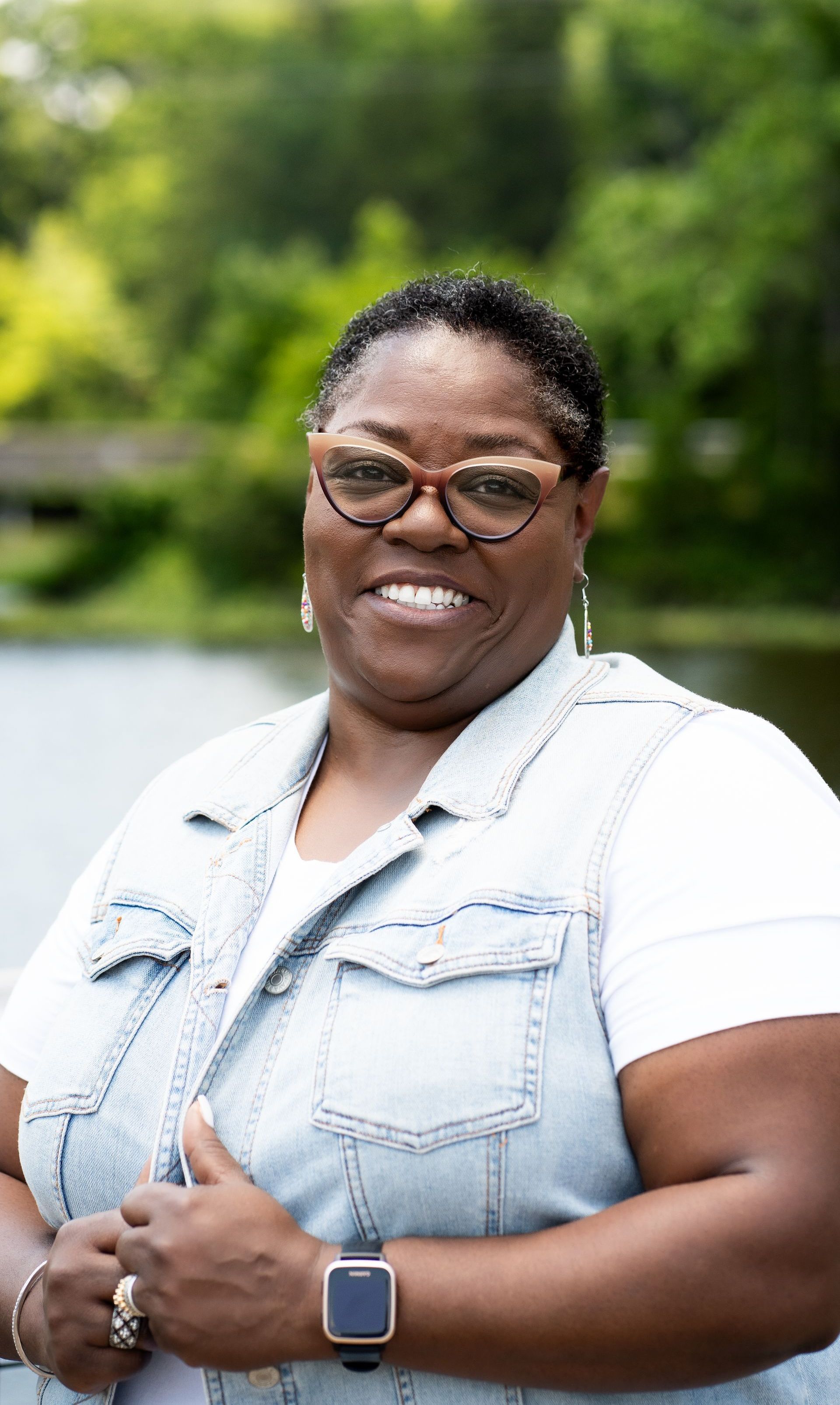 An image of Angela Bailey Page smiling with trees and water in the background