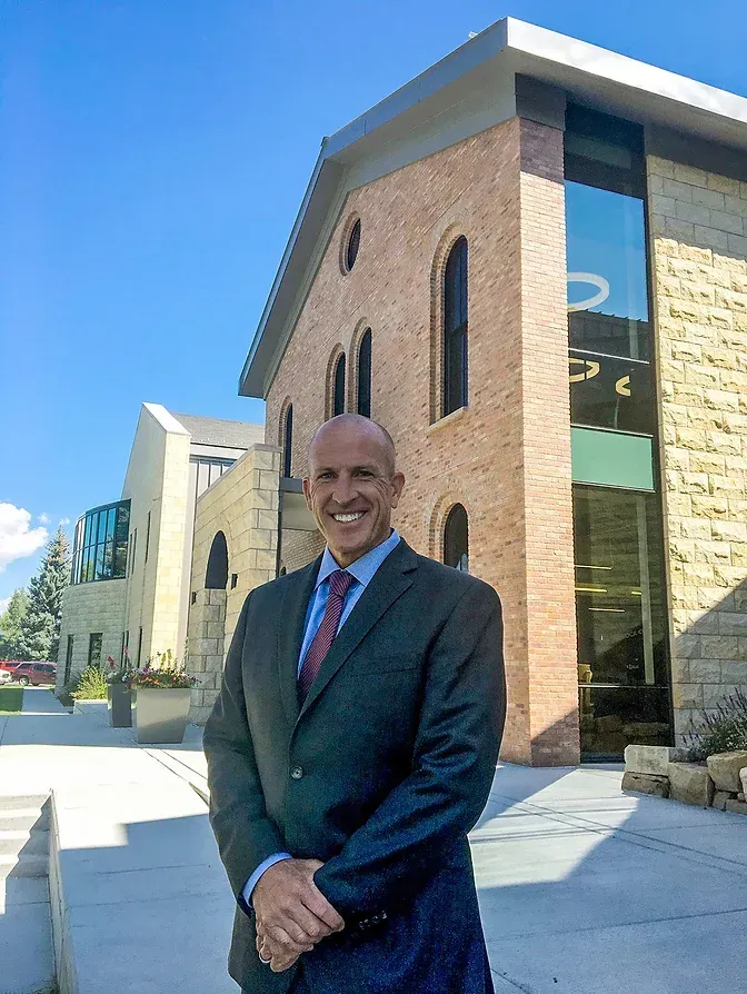 A man in a suit and tie is standing in front of a brick building.