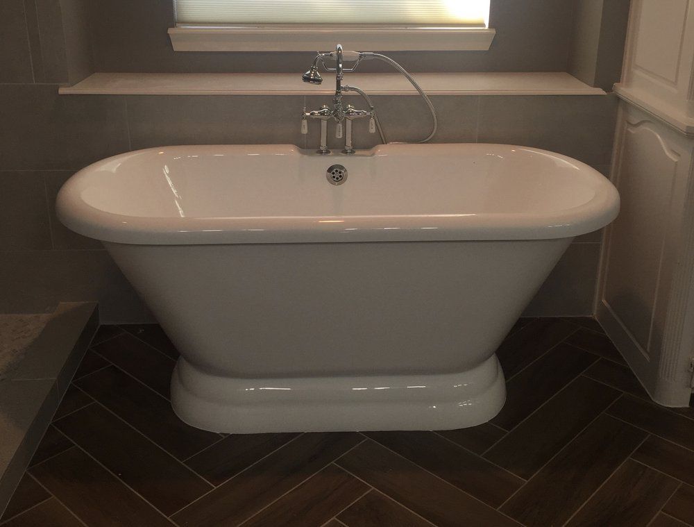 A white bathtub in a bathroom next to a window