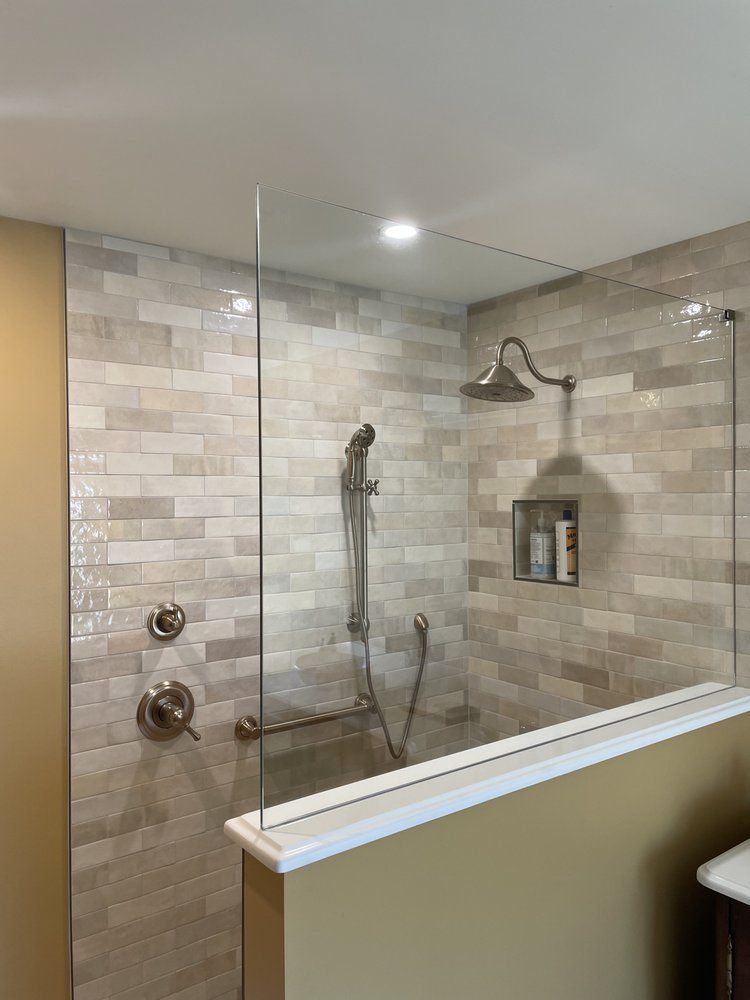 A bathroom with a walk in shower with a glass door and a shower head.