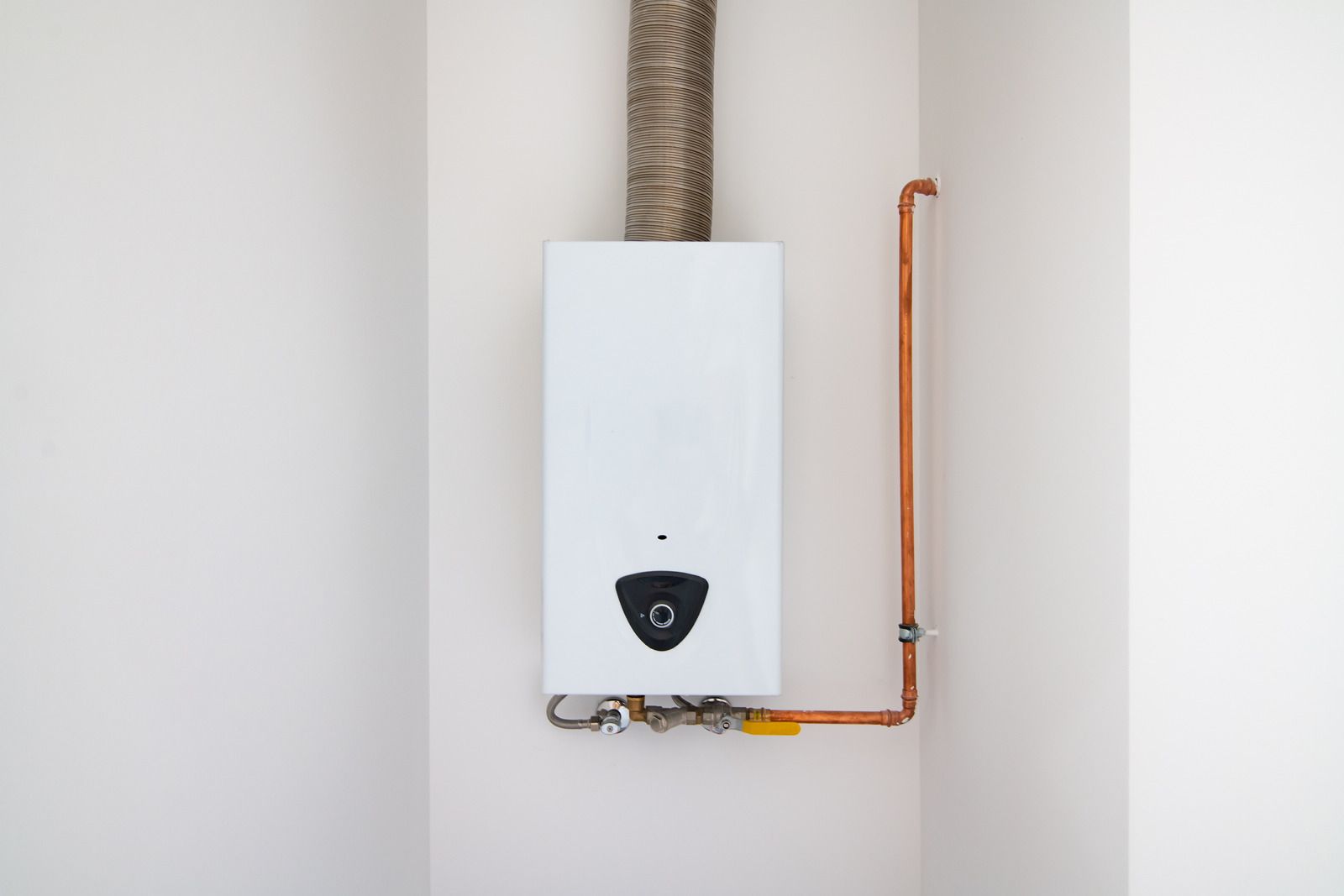 White wall-mounted boiler with copper pipes.