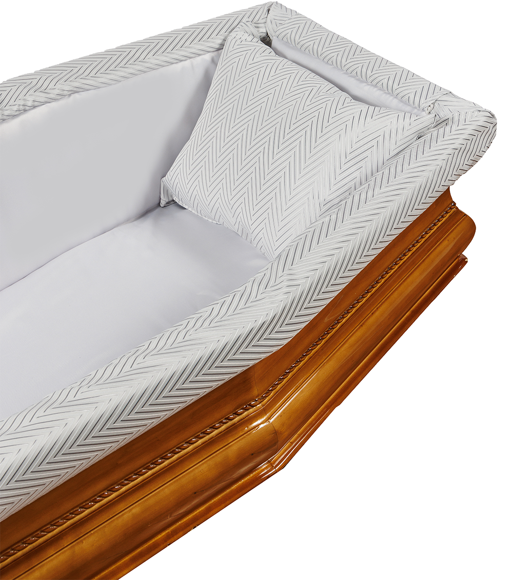 Interno di una bara in legno con biancheria bianca e un cuscino decorato.