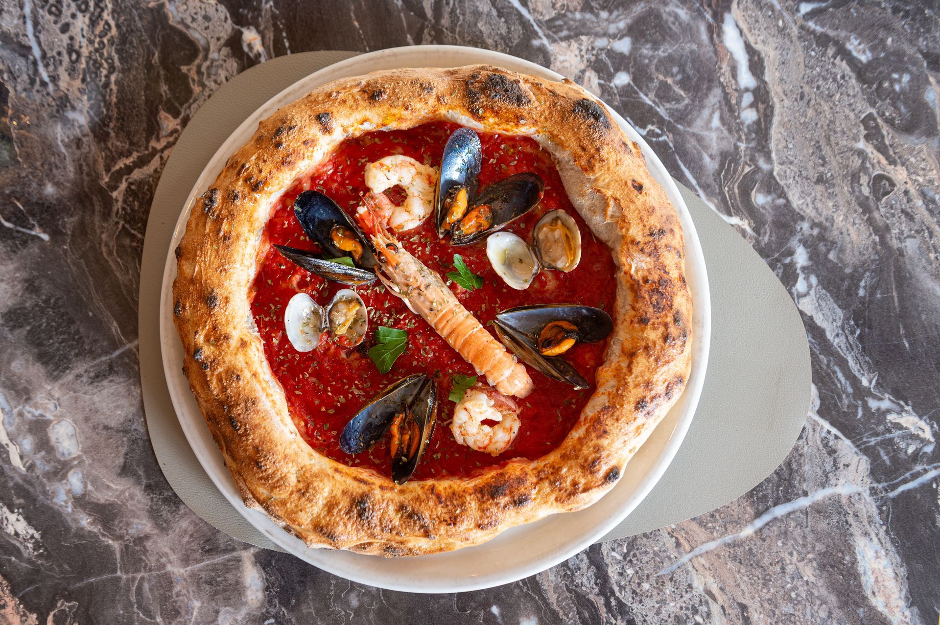 Una pizza con i frutti di mare è su un piatto su un tavolo.