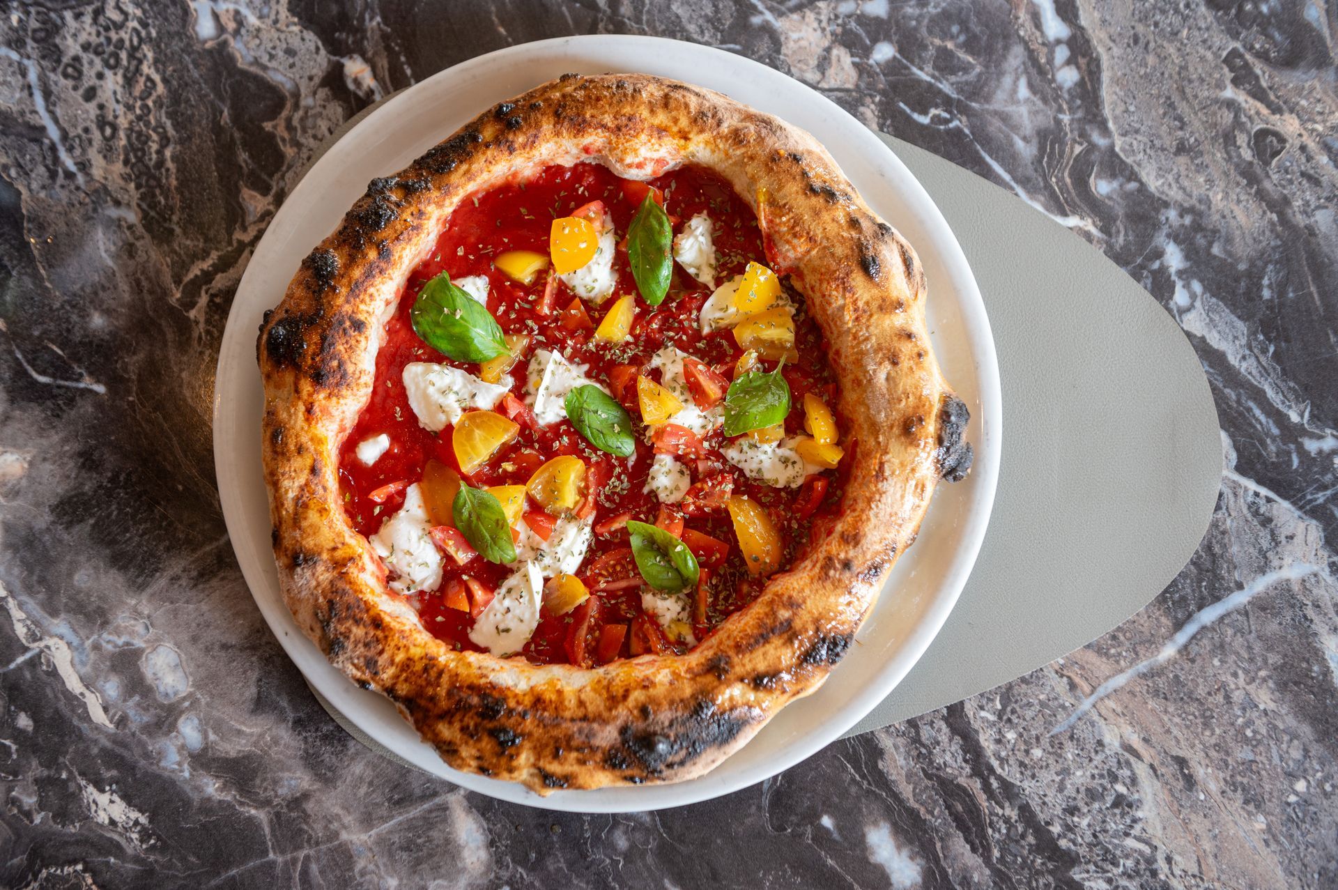 Una pizza è appoggiata su un piatto bianco su un tavolo.