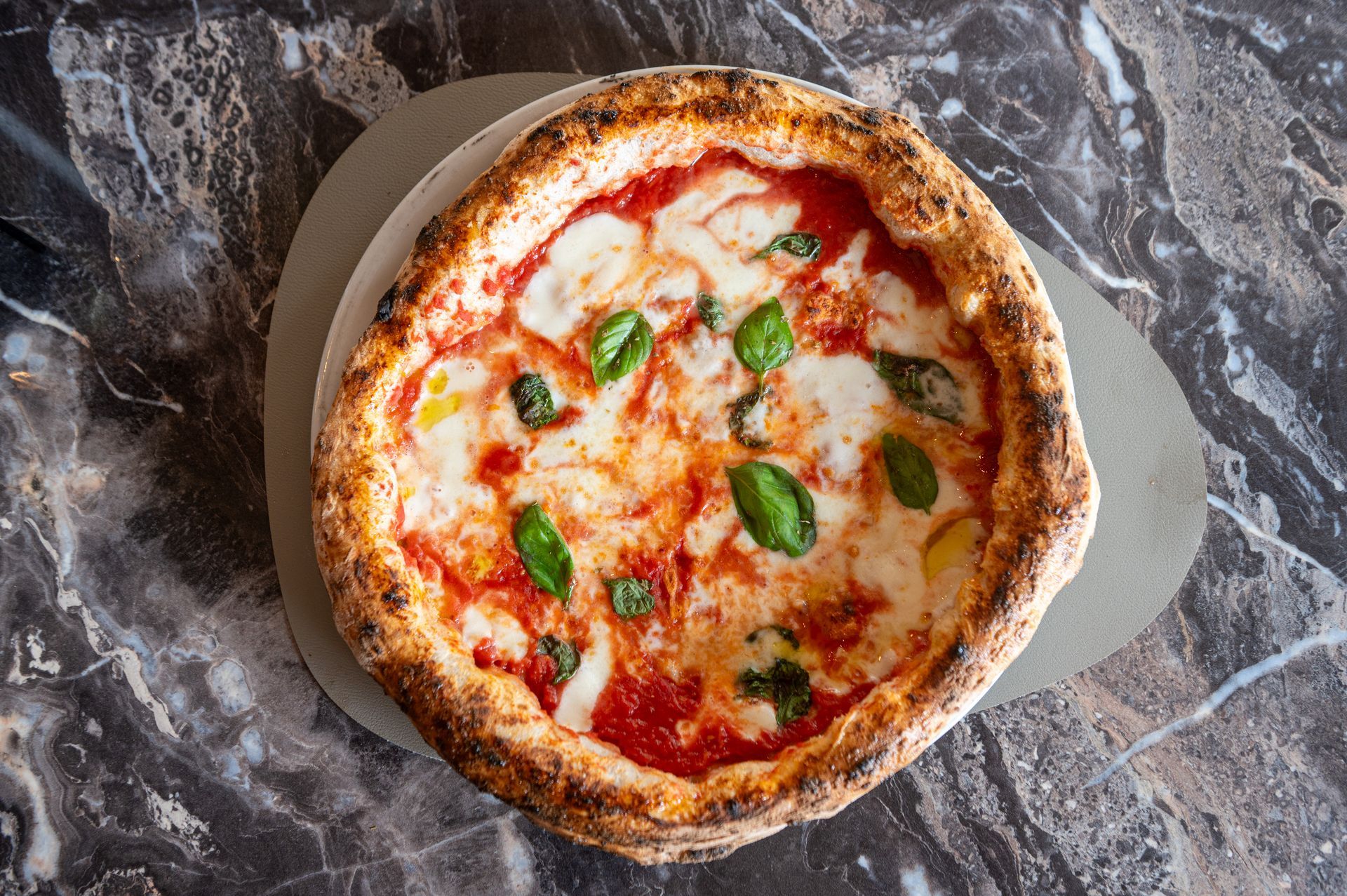 Una pizza è appoggiata su un bancone di marmo.