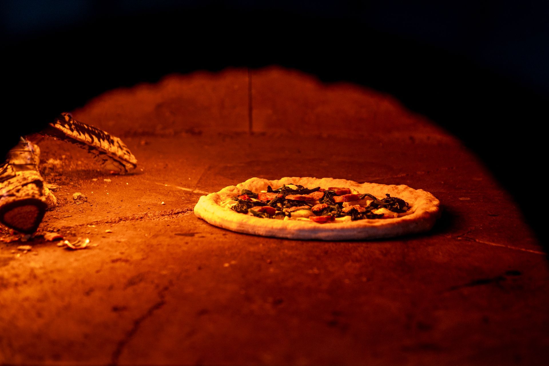 Una pizza viene cotta nel forno a legna.