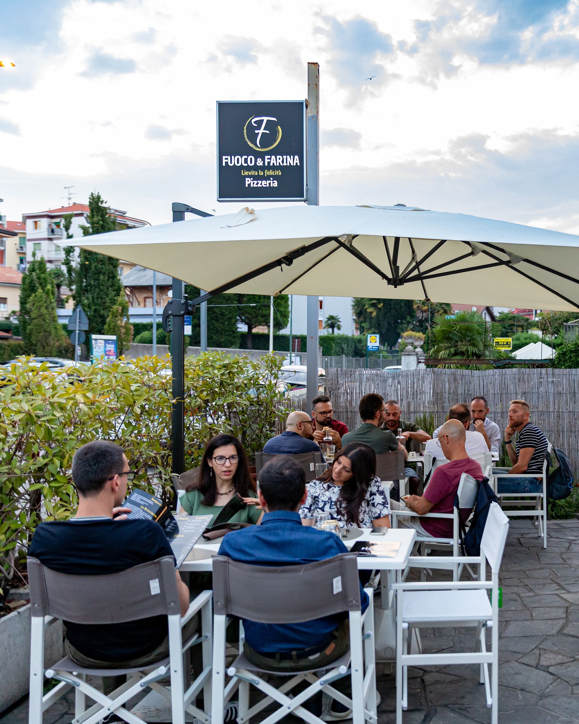 Una pizza con spinaci e salsiccia su un piatto bianco su un tavolo.