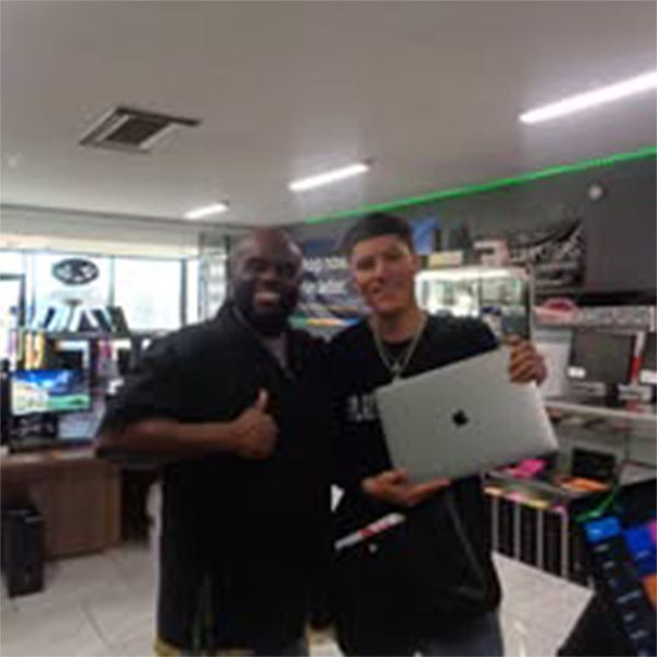 Two men standing next to each other holding an apple laptop