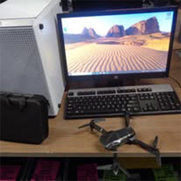 A drone is sitting on a desk next to a computer