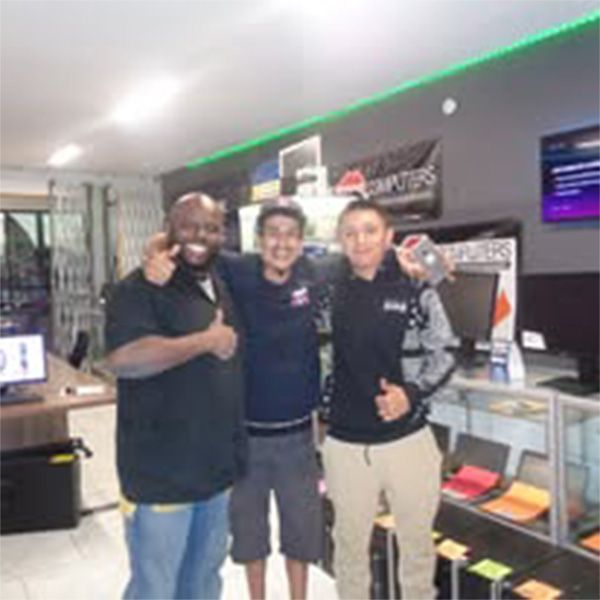 Three men are posing for a picture in a computer store.