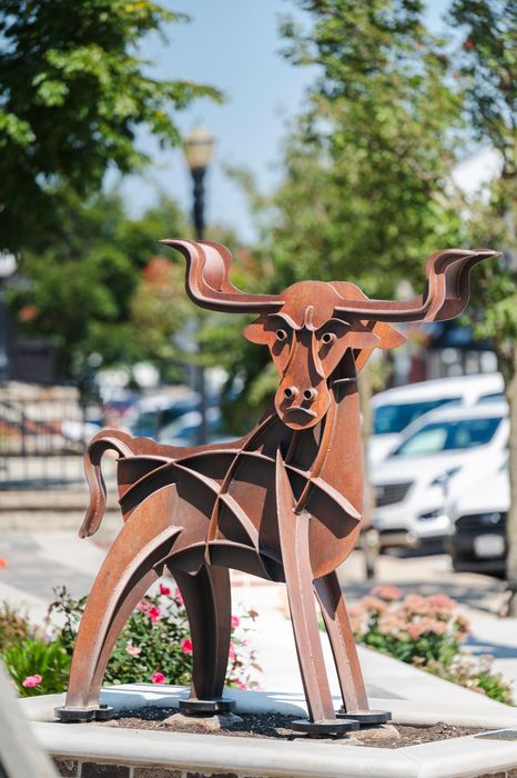 Large metal bull statue in front of a building with a sign that reads
