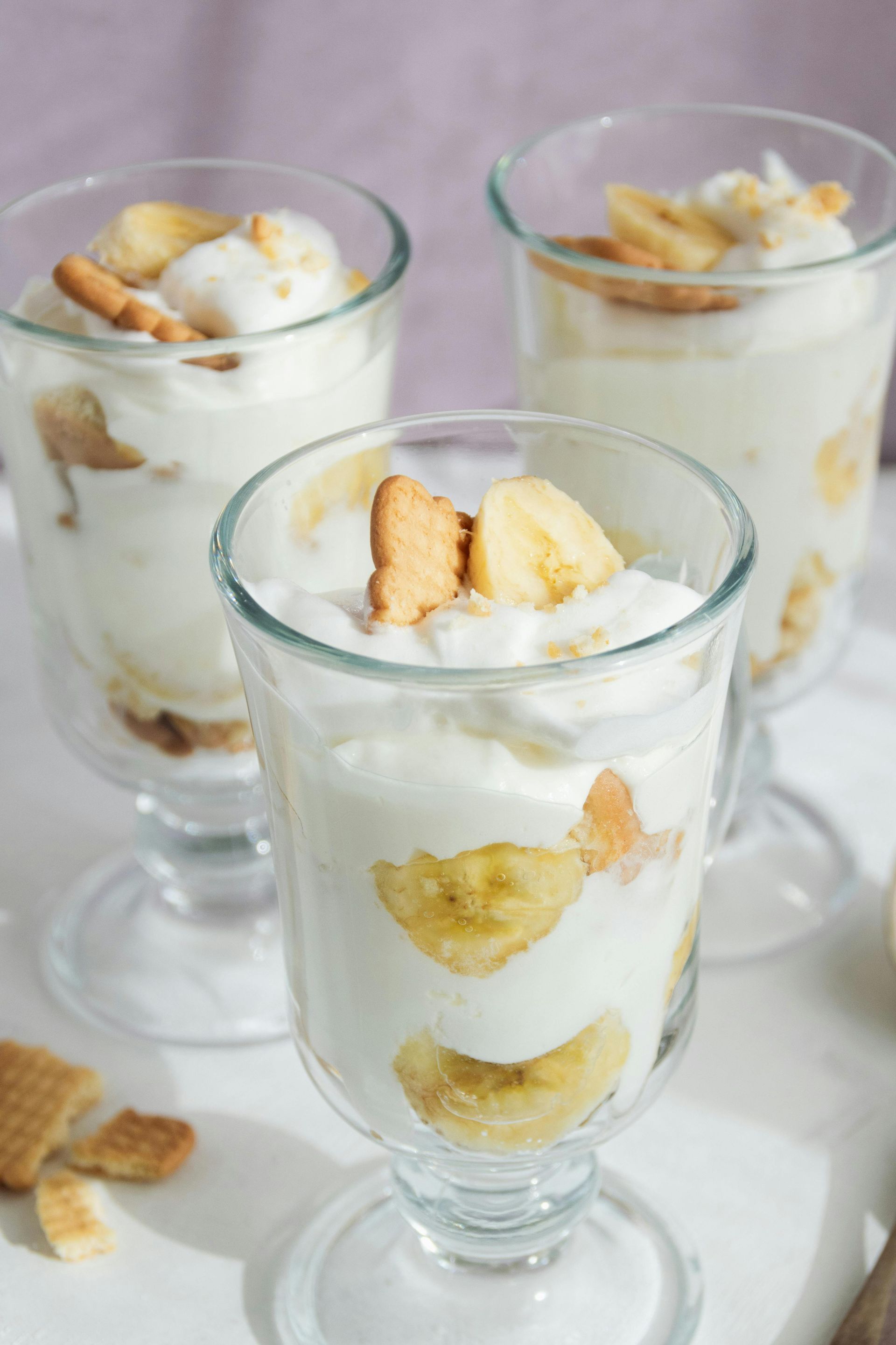 Banana pudding parfaits in clear glasses, layered with cookies and banana slices.