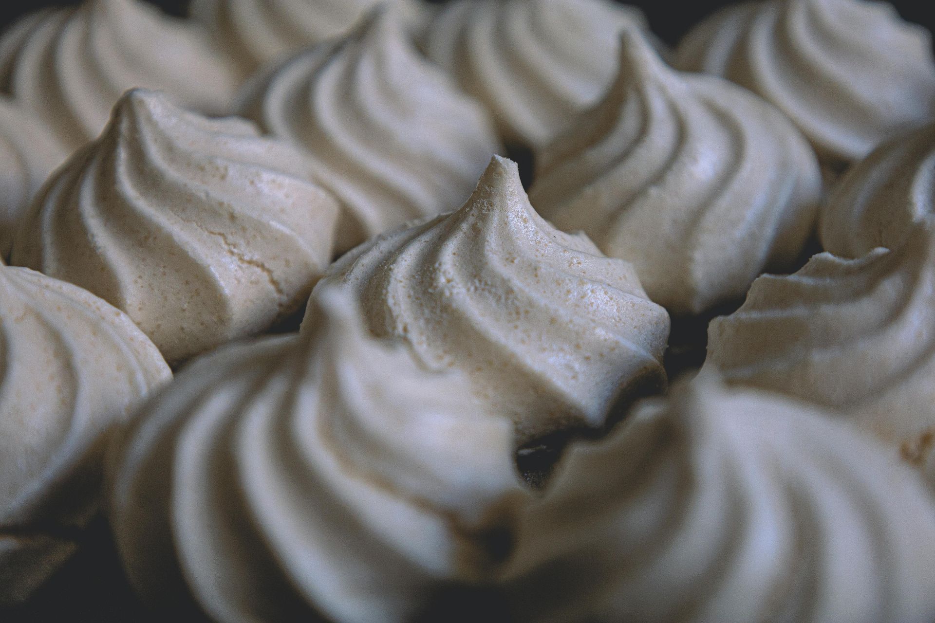 Close-up of a tray of swirled, light-colored meringue cookies.
