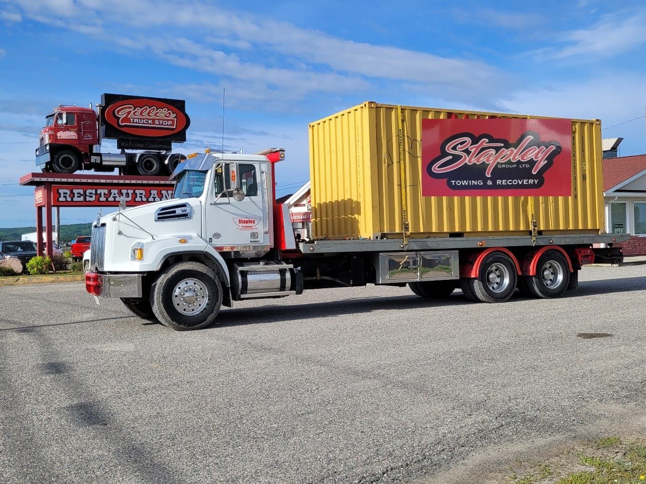 White truck with yellow cargo container, advertising 