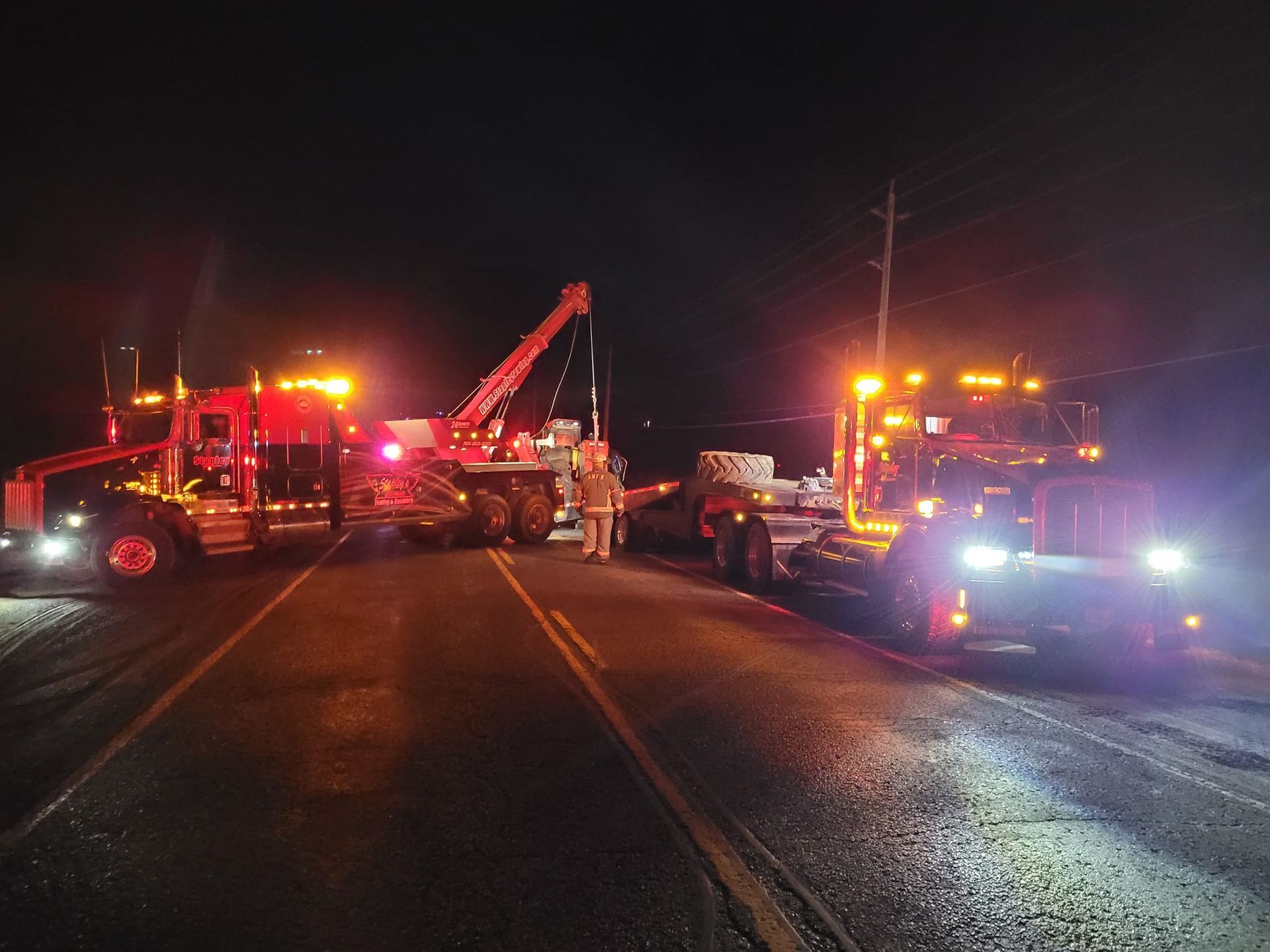 Tow trucks at night, road blocked, with emergency lights flashing, potential accident scene.