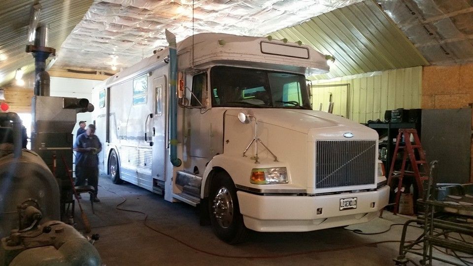 White truck-like vehicle inside a building; a person stands near the vehicle.