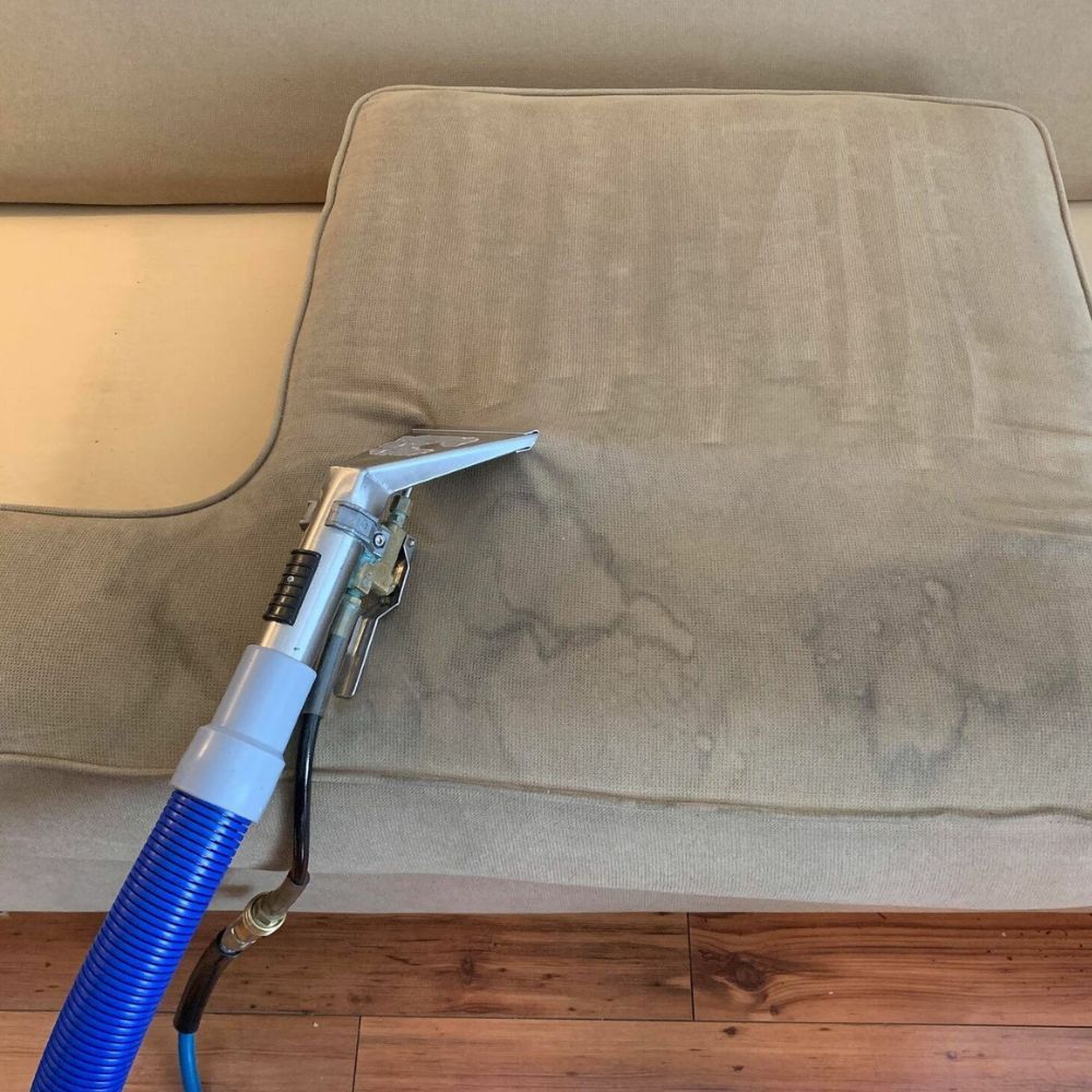 A vacuum cleaner is being used to clean a couch