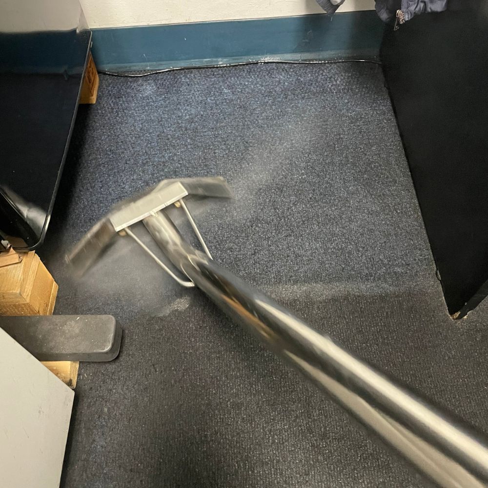 A vacuum cleaner is cleaning a carpet in a room.