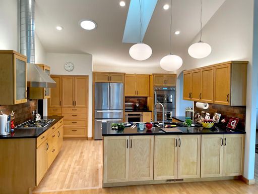 Bright modern kitchen with light wood cabinets, island, stainless steel appliances, and pendant lights