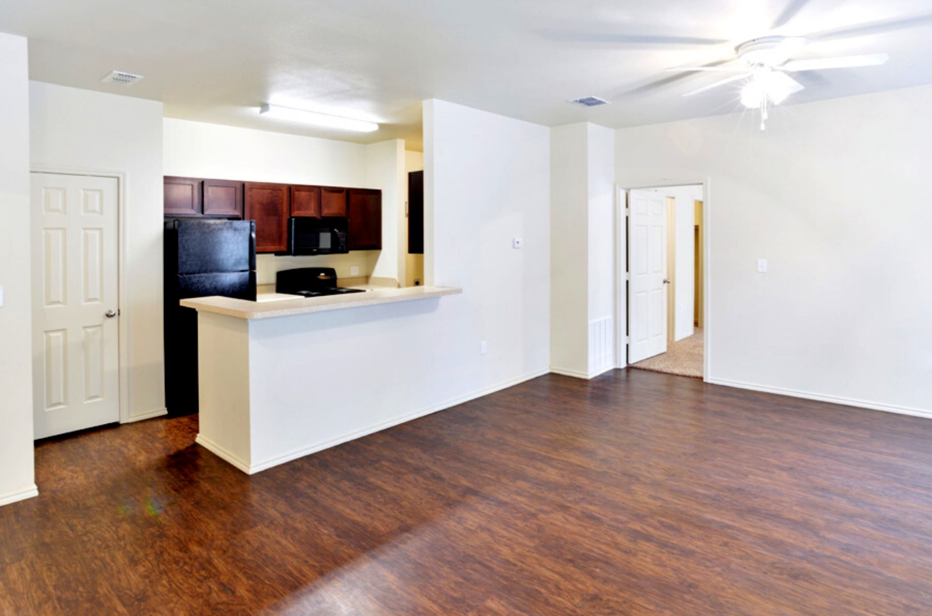Interior of living room with view of doorway and kitchen separated by half-height wall