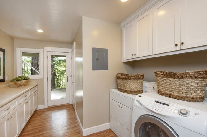 Laundry room with white cabinets, washer, dryer, and doorway to outside.