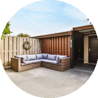 A patio with a sectional couch and a wooden fence