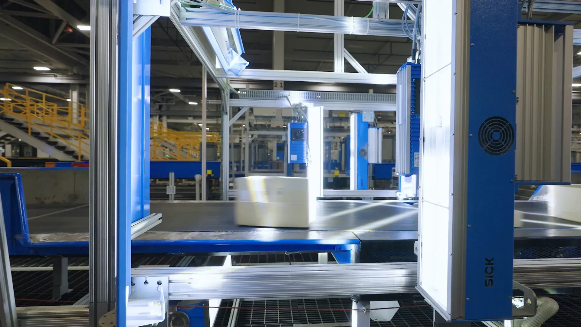 Automated industrial machine in a factory setting, with blue and silver structures, moving parts.