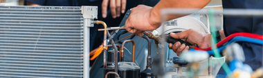 Technician repairing air conditioner with tools and wires visible indoors