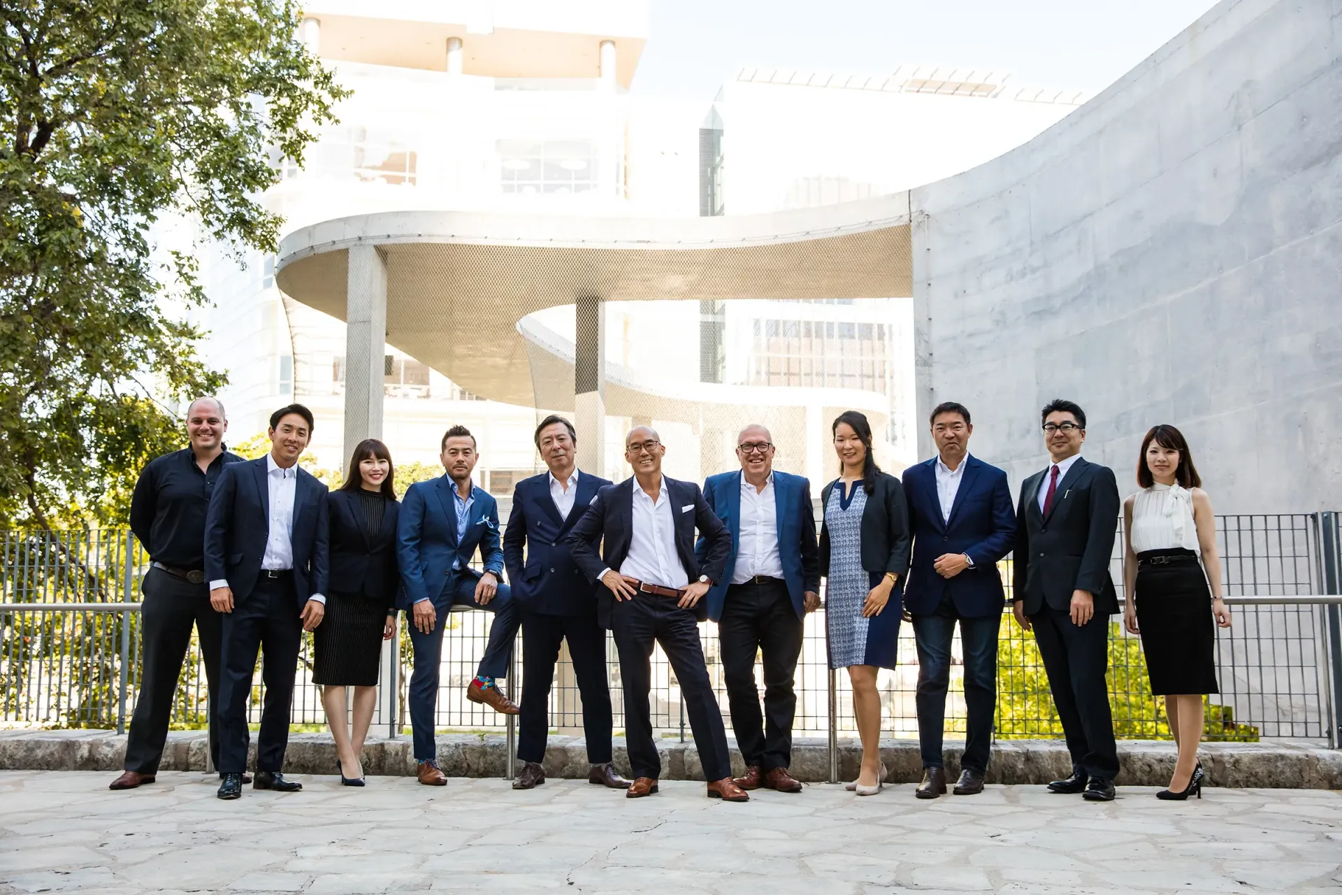 A group of business people are posing for a picture in front of a building.