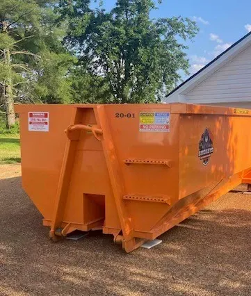 A large orange dumpster is parked in front of a house.