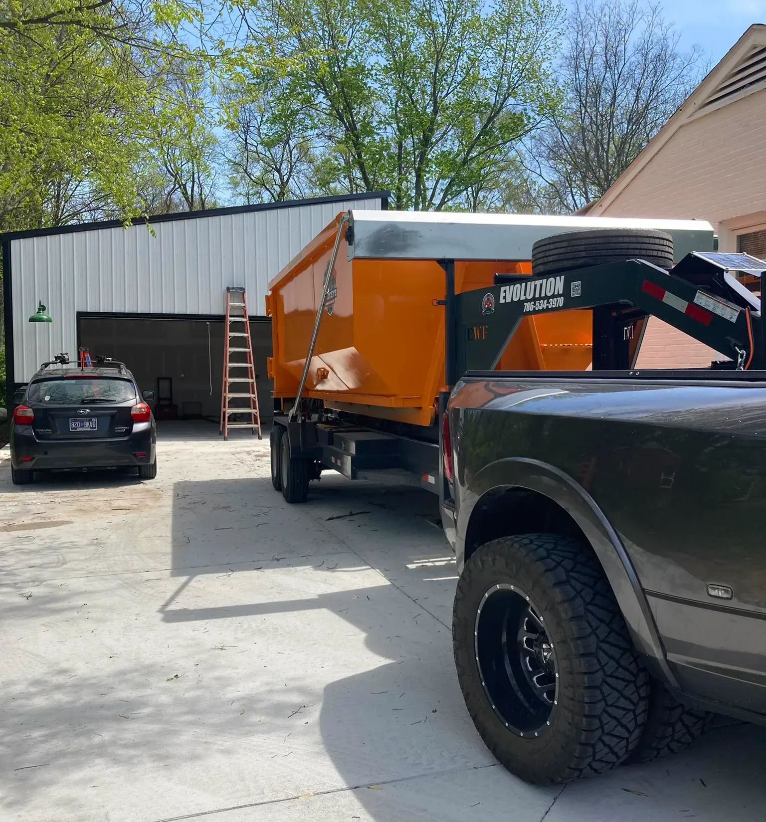 A green dumpster is parked in front of a house.