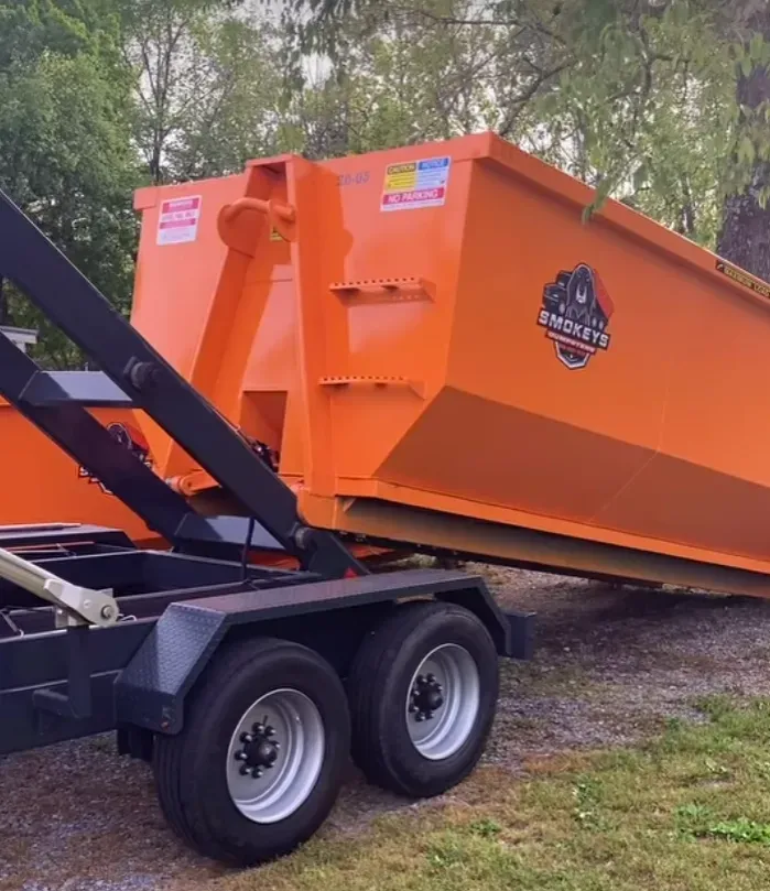 A green dumpster is parked in front of a house.