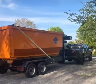A green dumpster is sitting in a warehouse next to a truck.