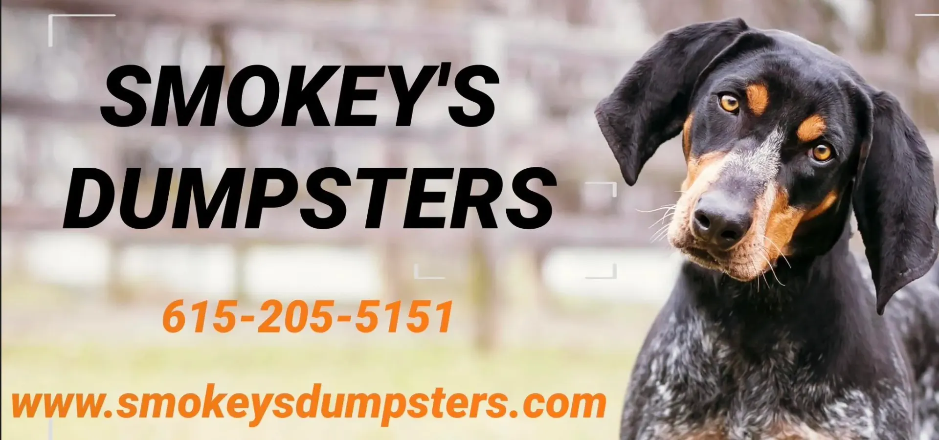 A dumpster is being towed by a truck in front of a building.