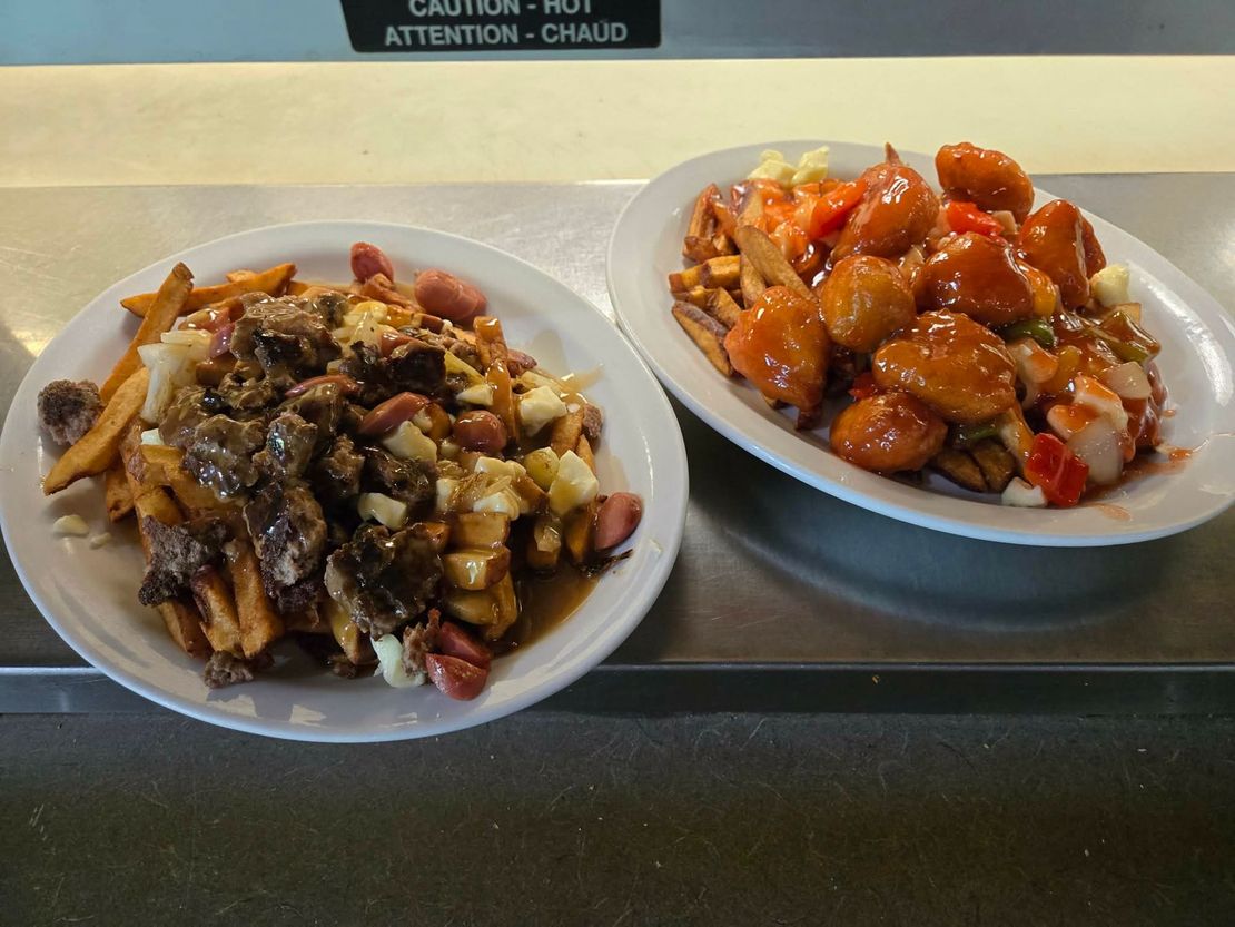 Deux assiettes de poutine, l'une avec de la viande et des hot-dogs et l'autre avec du poulet glacé à l'orange, sur un comptoir.